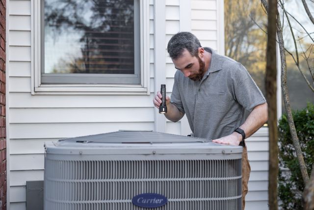 a%20person%20outside%20checking%20an%20hvac%20unit%20with%20a%20flashlight